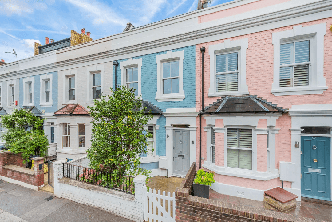 Pastel blue and pink painted terraced houses with white trim on a quiet Fulham street