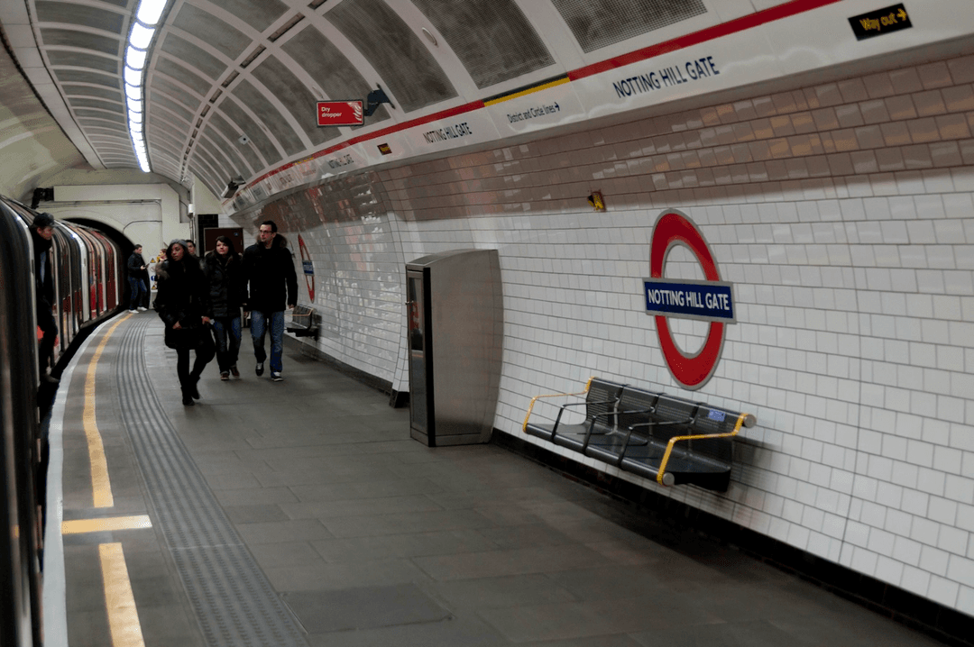 Notting Hill Gate Underground station platform with TfL roundel sign and commuters walking