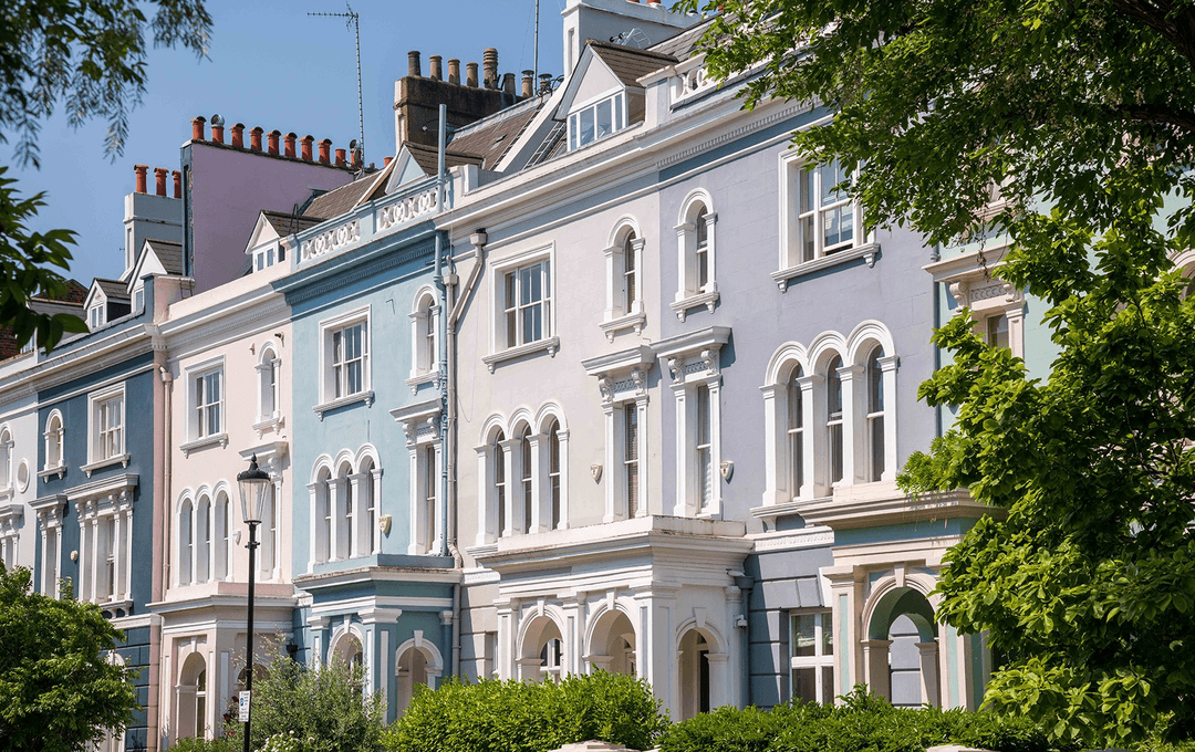 Grand Notting Hill rendered townhouses painted in pastel lilac and blue with arched sash windows