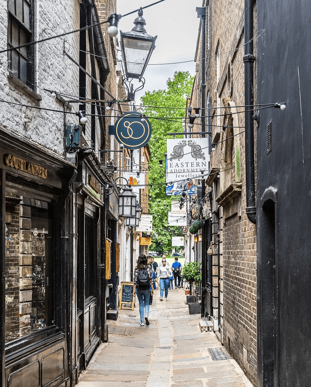 Narrow cobblestone alleyway in Richmond lined with Victorian buildings and hanging pub signs