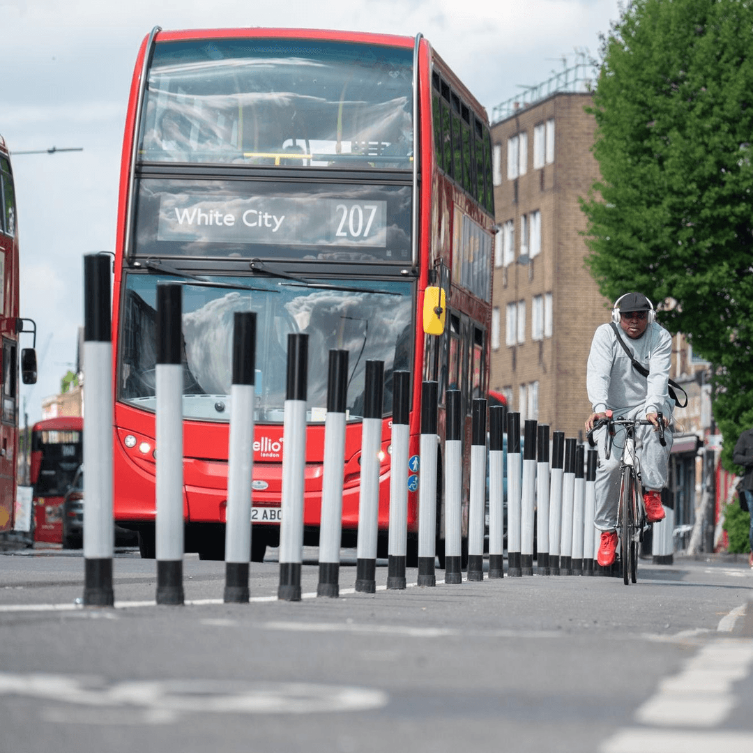 Red double-decker bus 207 to White City with a cyclist in a protected cycle lane alongside