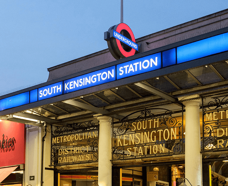 South Kensington Underground station entrance illuminated at dusk with Metropolitan and District Railways ironwork signage